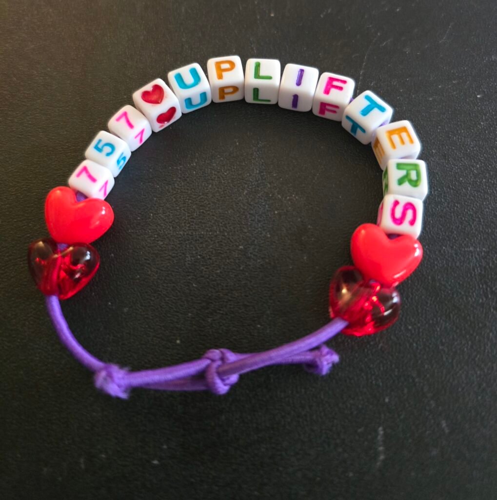 A charm that says "757 Uplifters", with a heart icon between the 757 and the word uplifters!