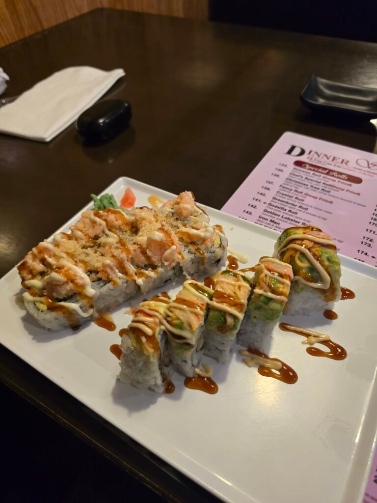 Sushi rolls with sauce on a white plate in a restaurant