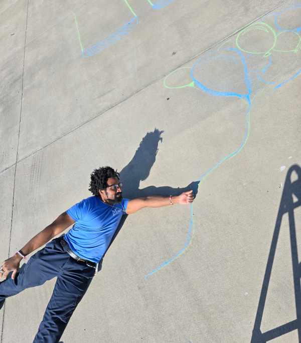 A man on the ground, looking as if he will be pulled into the sky by balloons that are drawn on the ground.